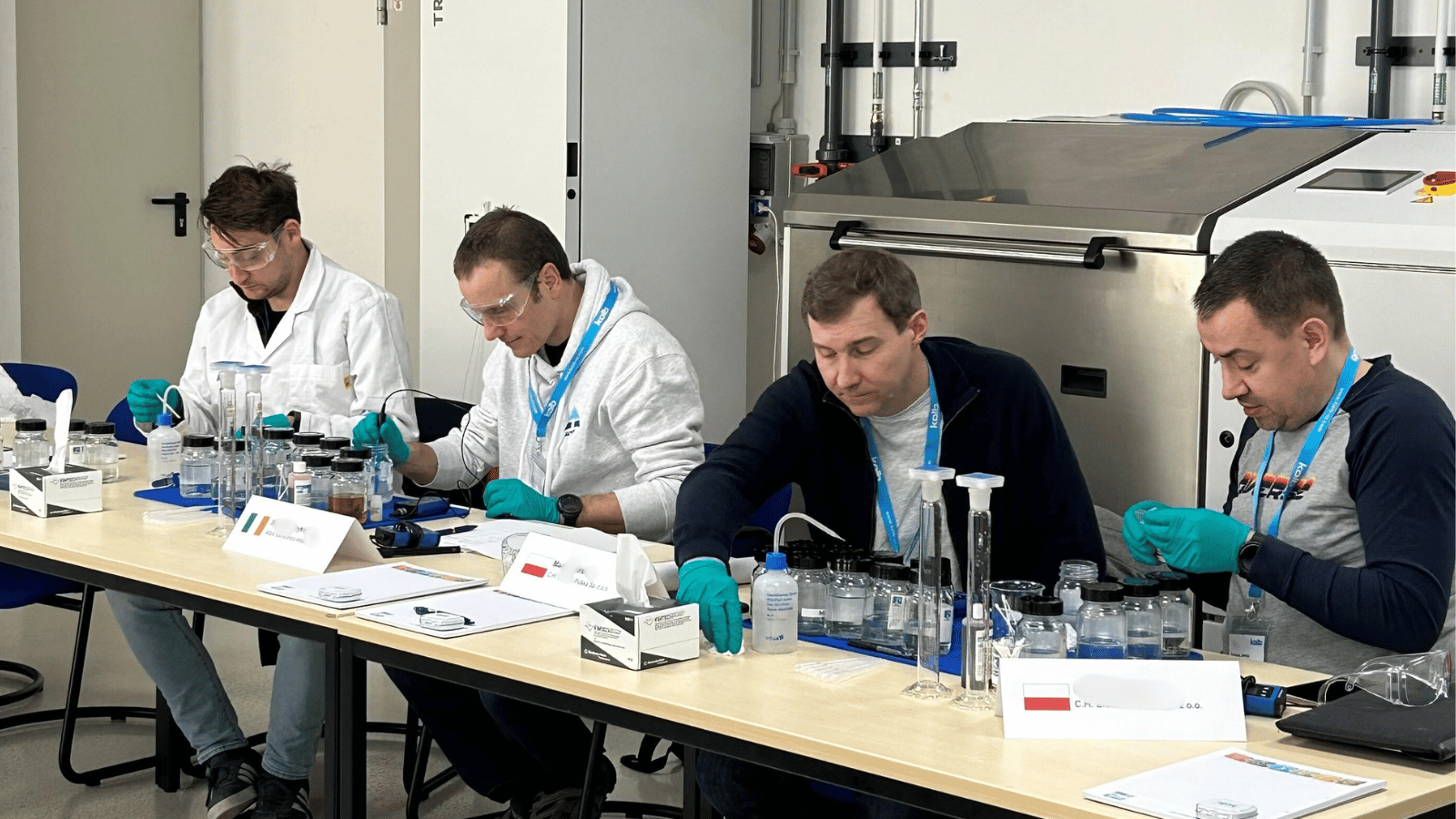 Four participants at the campus, wearing protective gear, are conducting chemistry experiments 